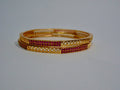 Gold bangles with red stones on a white background