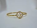 Gold cuff bracelet with a circular design featuring triangular cut stones on a white background