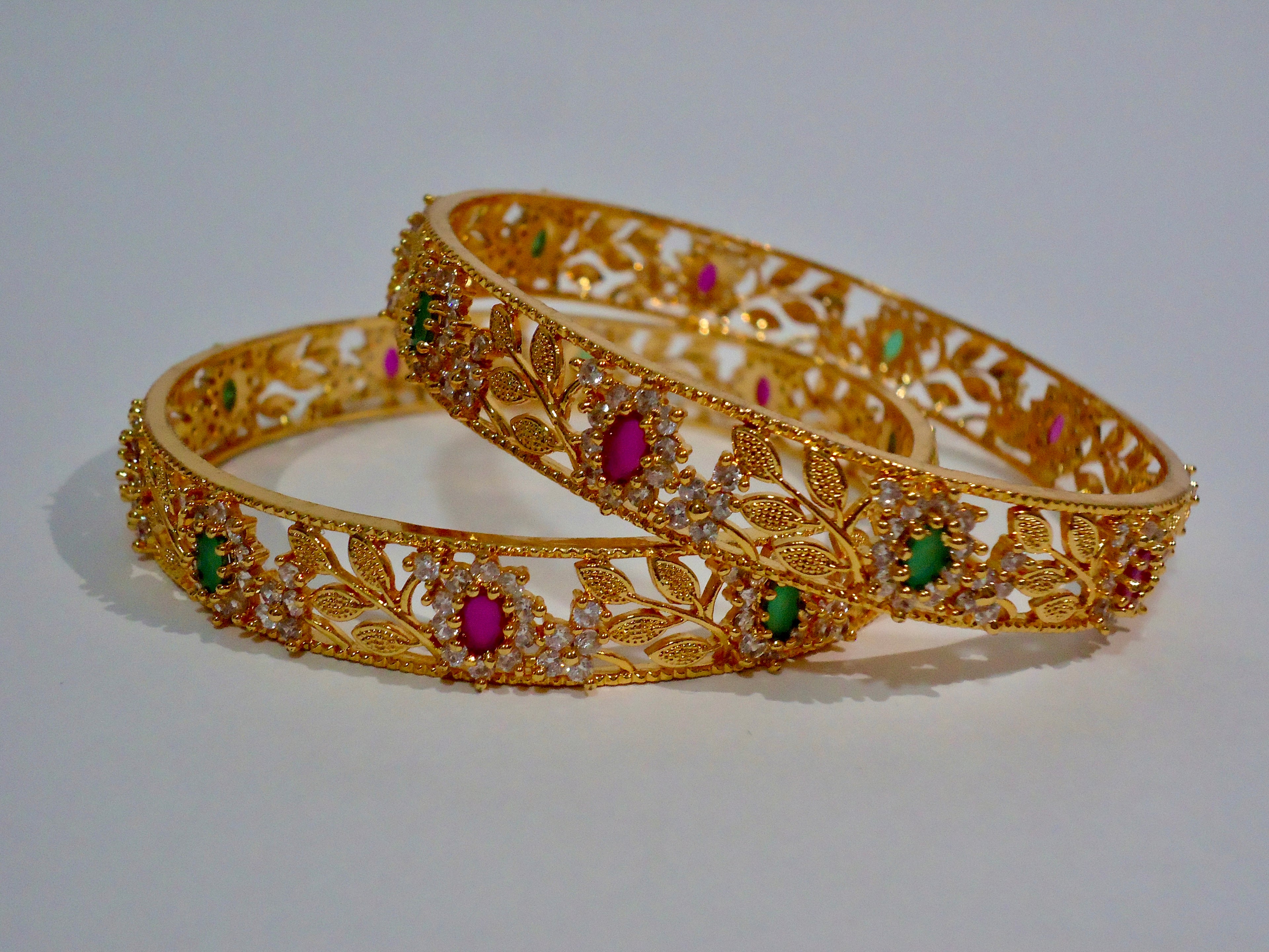 Gold bangles with gemstones on a white background
